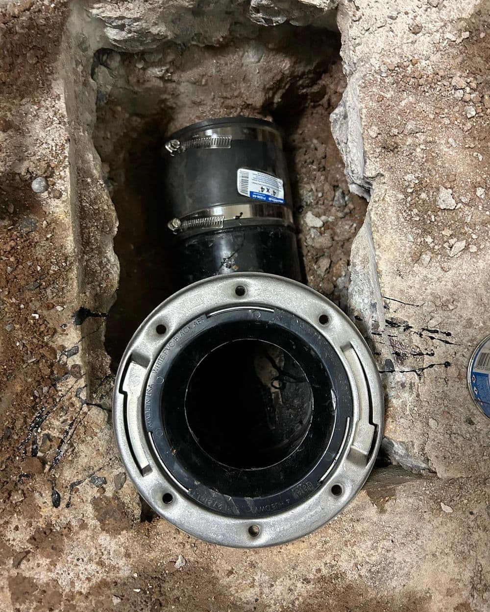 PVC pipe connection in a trench with exposed soil and gravel, showing installation progress.