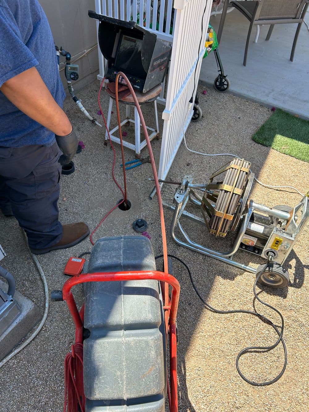Technician using equipment for plumbing maintenance in residential yard.